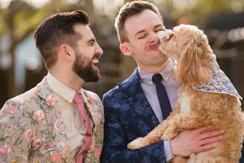 Two grooms kissing their puppy