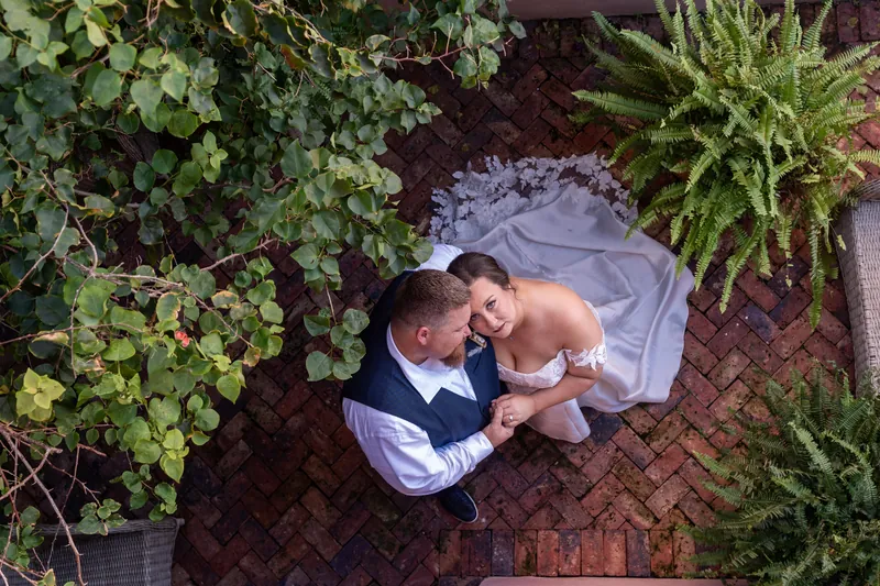 Aerial view of couple on brick courtyard with lush greenery