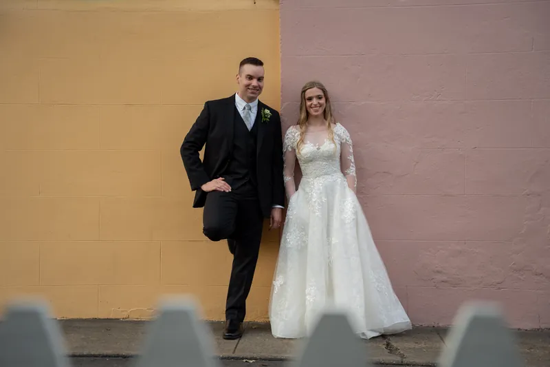Wedding couple portrait against colorful pink and gold wall downtown
