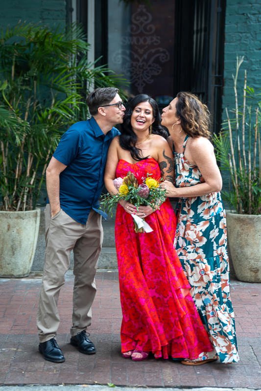 0026_A joyful moment as two people kiss a person holding a bouquet in the middle.jpg