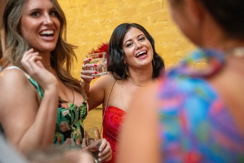 0029_Two women enjoying a lively conversation and drinks at a vibrant gathering.jpg