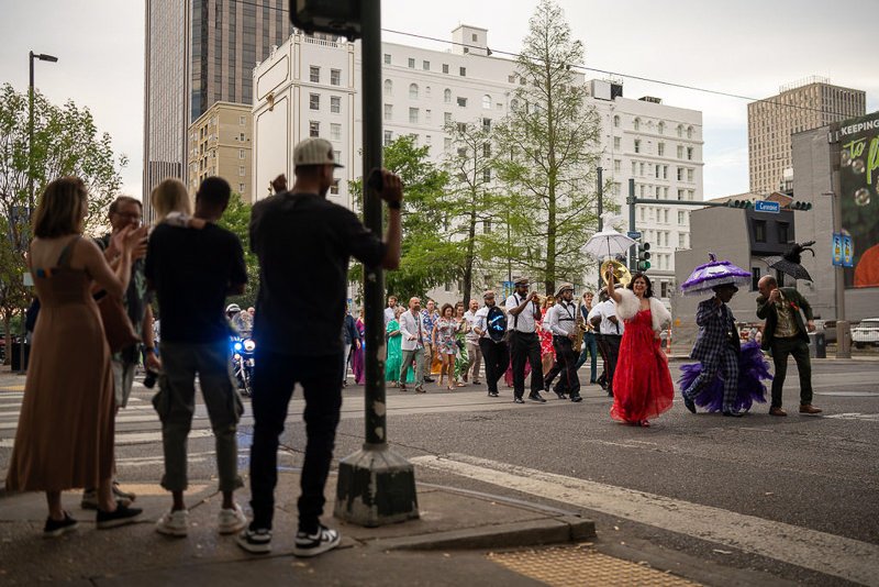 0033_People in vibrant costumes parade through a city street while onlookers capture the moment.jpg