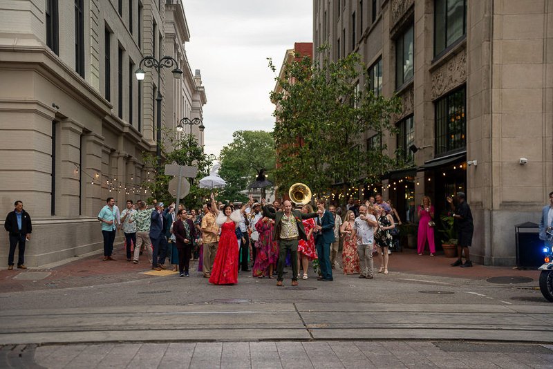 0034_A lively street parade with musicians and people in colorful outfits celebrating between tall city buildings.jpg