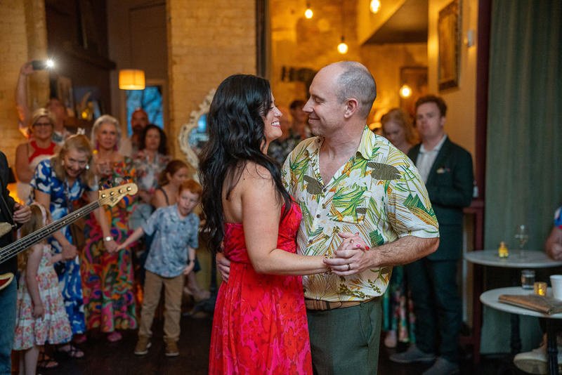 0036_A couple dancing and smiling at each other during a lively party with friends in the background.jpg