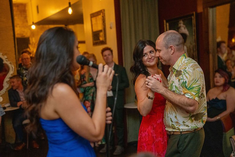 0037_A couple shares a romantic dance while a singer performs for an attentive audience in a cozy dimly lit setting.jpg