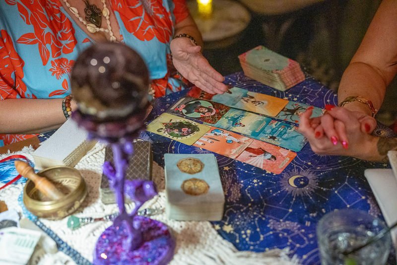 0039_A tarot card reader interprets cards during a mystical session with a crystal ball and various decks on the table.jpg