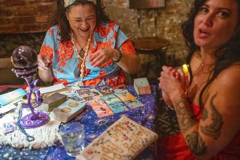 0041_Two women sharing a joyful moment while reading tarot cards at a cozy dimly lit setting.jpg