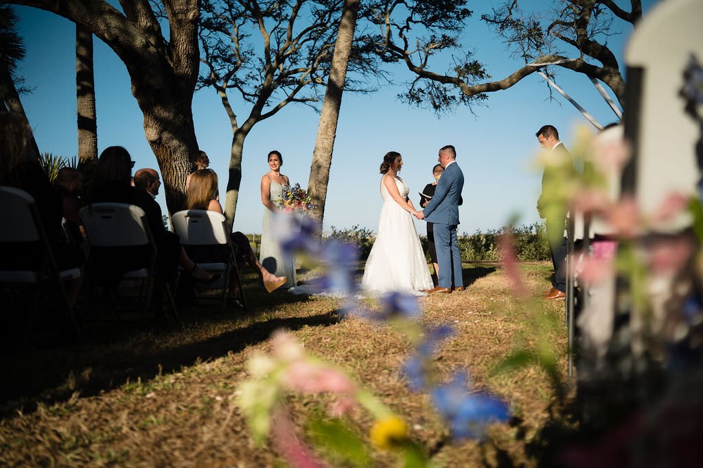 A beautiful outdoor wedding ceremony with the bride and groom exchanging vows under the shade of trees.jpg