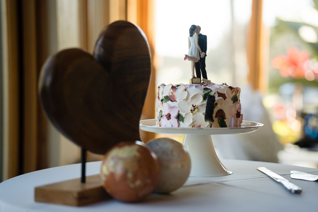 A beautiful wedding cake with a heart shaped wooden sculpture and a golden globe nearby.jpg