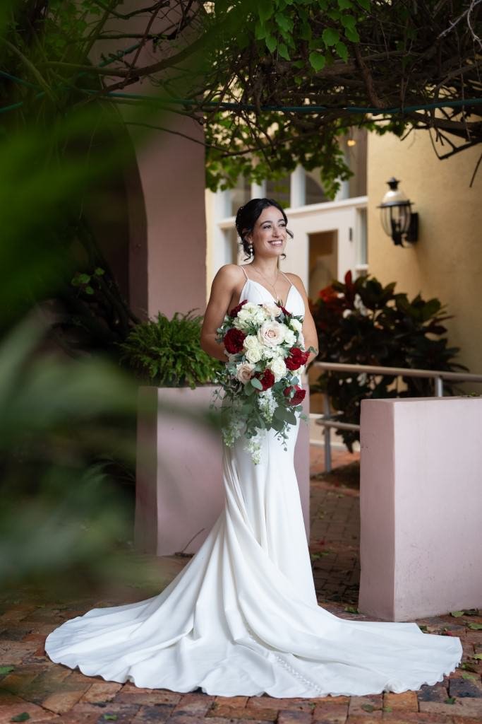 A bride stands gracefully in a white gown with a bouquet of flowers.jpg