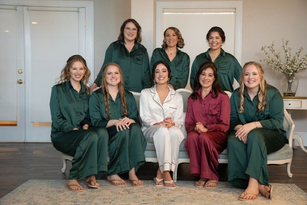 A group of women in matching pajamas seated and standing indoors smiling for the camera.jpg