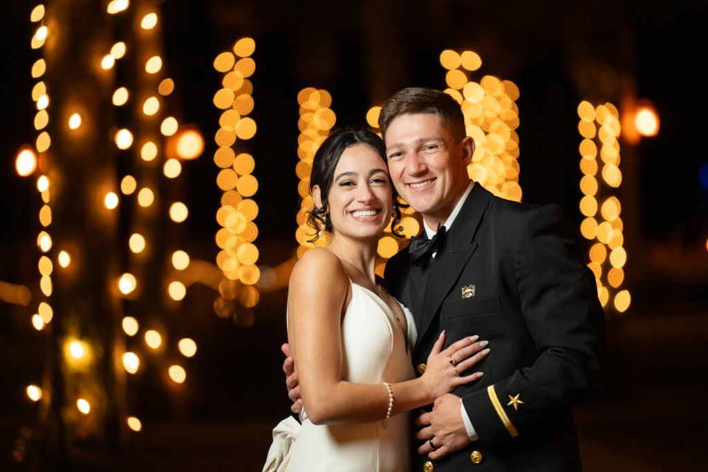 A happy couple in formal attire smiling and embracing with beautiful bokeh lights in the background.jpg