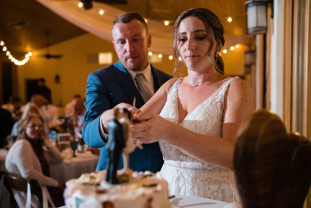 A newly married couple cuts their wedding cake surrounded by their loved ones wedding cake love celebration.jpg