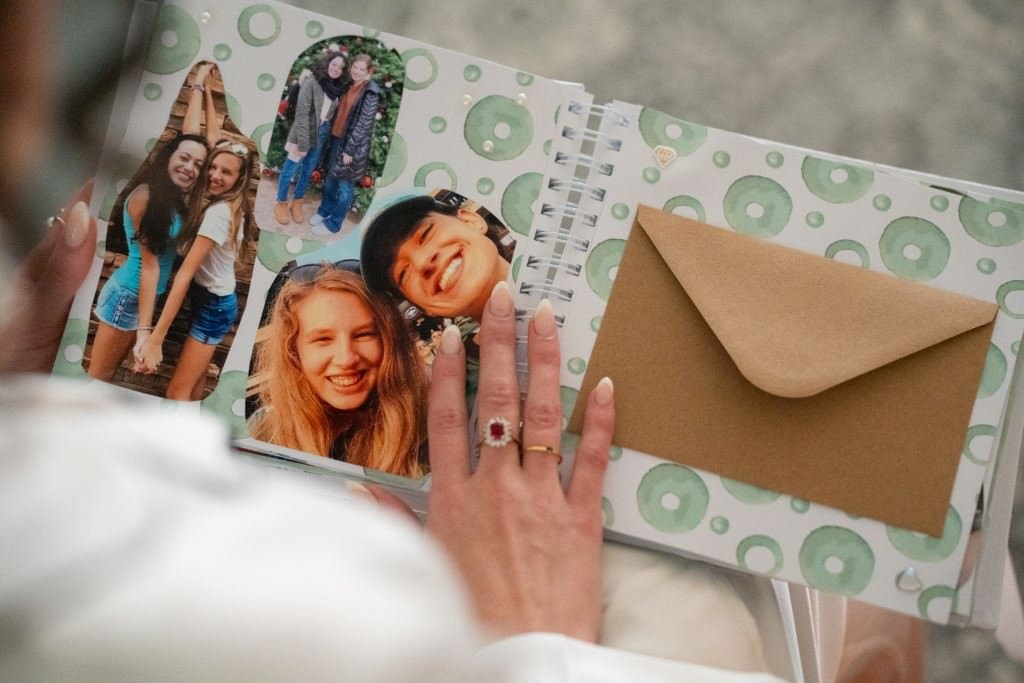 A person looks at a scrapbook filled with cheerful photos and an envelope.jpg