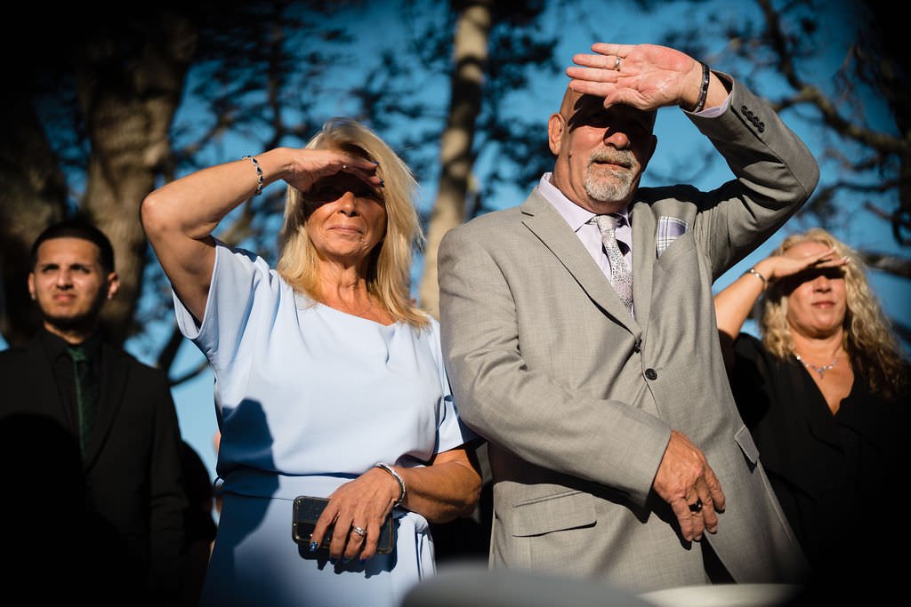 A wedding guest shields their eyes from the bright sun during the ceremony.jpg