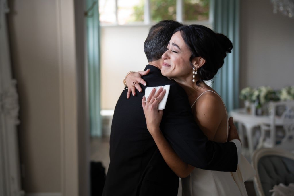A woman and a man share a heartfelt embrace in a warmly lit room.jpg
