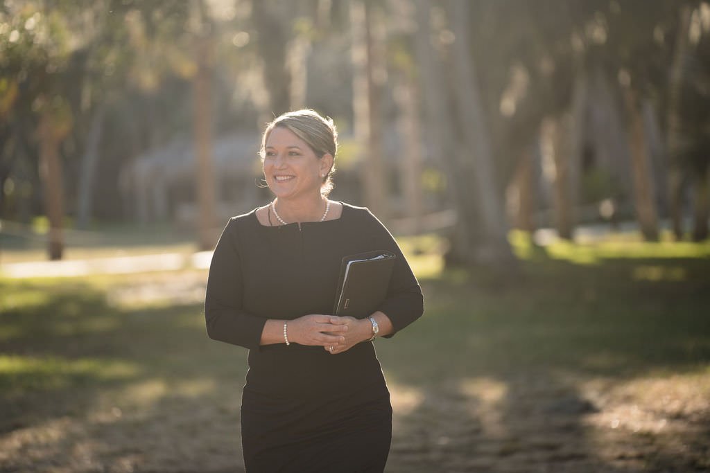 A woman in a black dress walks through a park holding a black folder She looks confident and ready for the day ahead.jpg