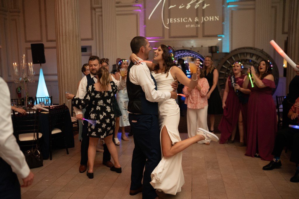 Bride and groom share a joyful dance at their wedding reception surrounded by cheering guests.jpg