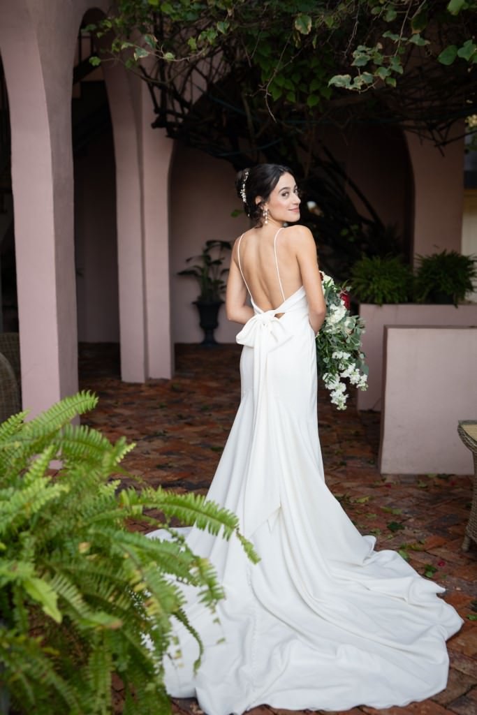 Bride in a stunning white gown smiles over her shoulder showcasing the elegant train and open back of her dress.jpg