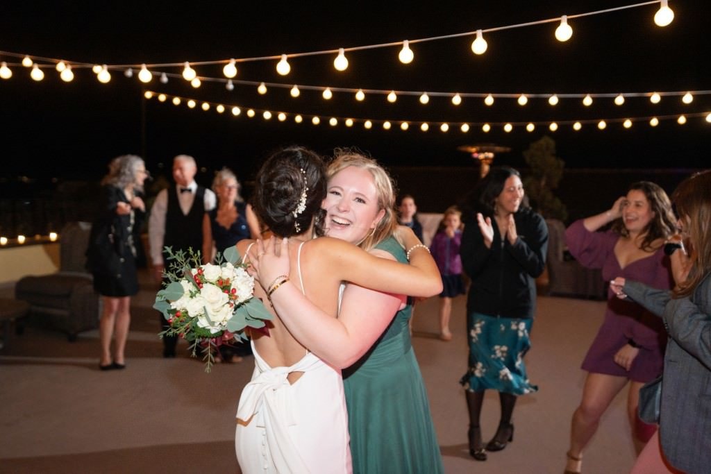 Friends embrace on a beautifully lit outdoor dance floor sharing a joyful moment at a nighttime celebration.jpg