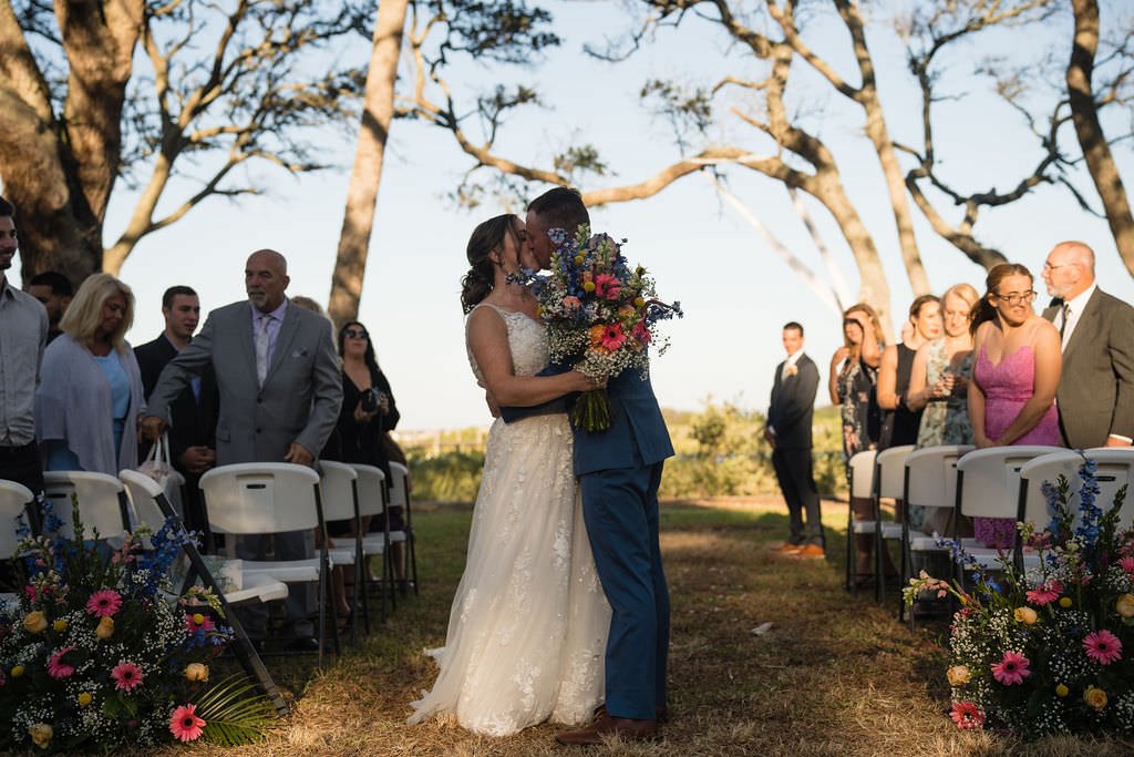 Newlyweds share a kiss after saying I do under the shade of the trees wedding justmarried love couple ceremony kiss.jpg