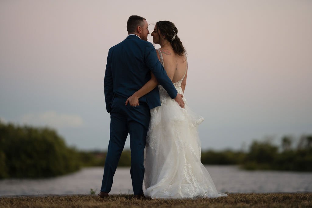 Newlyweds share a loving moment by the water at sunset.jpg