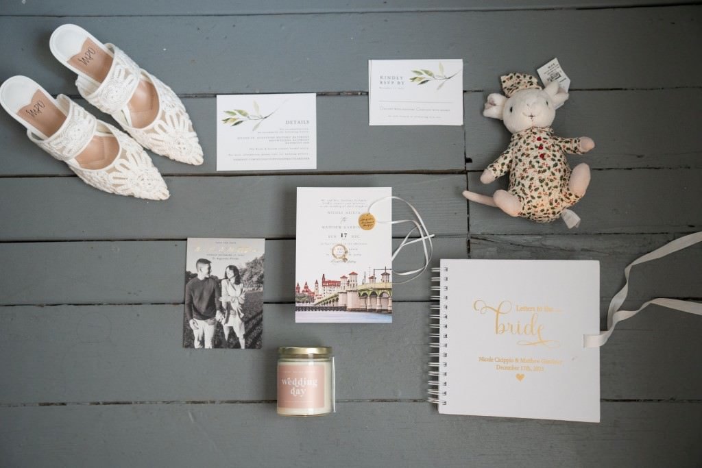 Wedding day details with shoes invitations a candle a bridal book and a cute stuffed toy.jpg