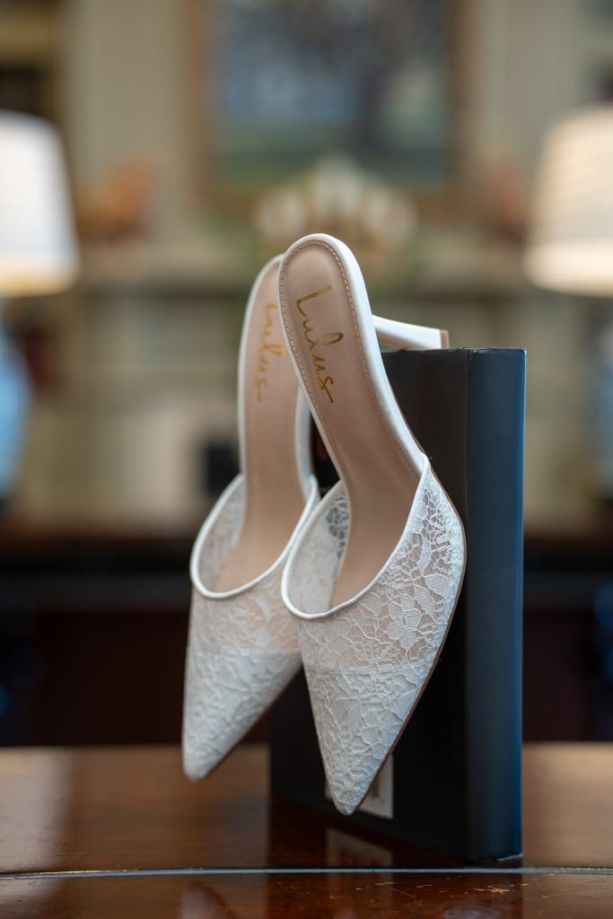 Elegant white lace heels displayed.jpg