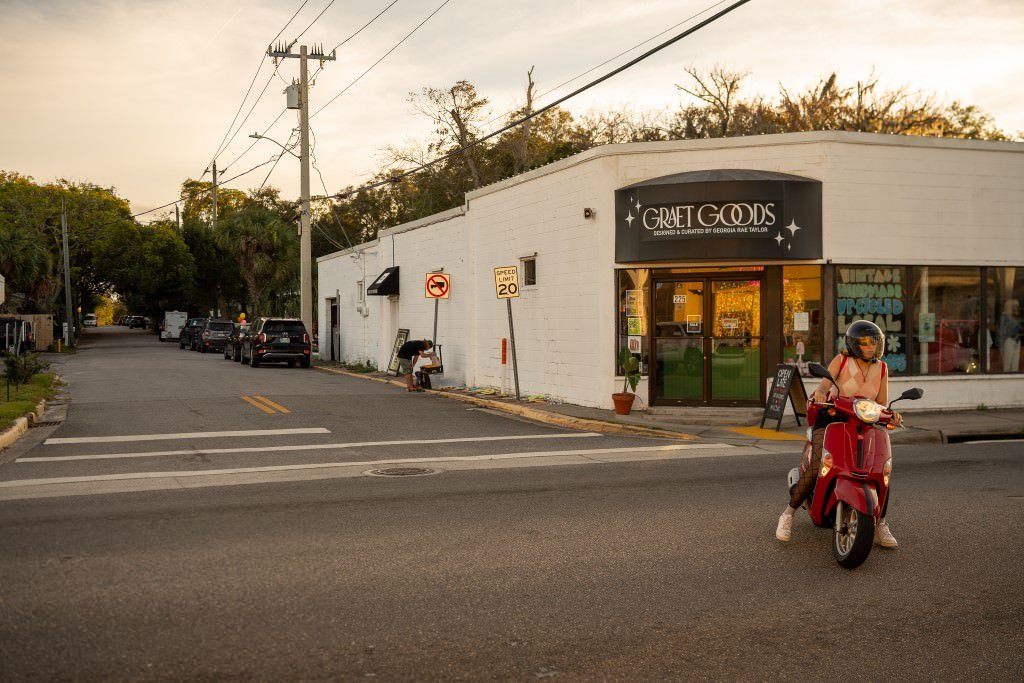 Person riding scooter past shop.jpg